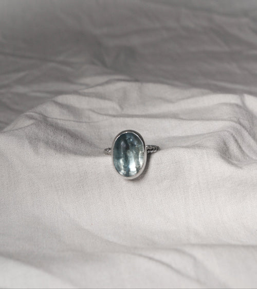 blue gemtsone on Silver ring  on a textured white fabric surface