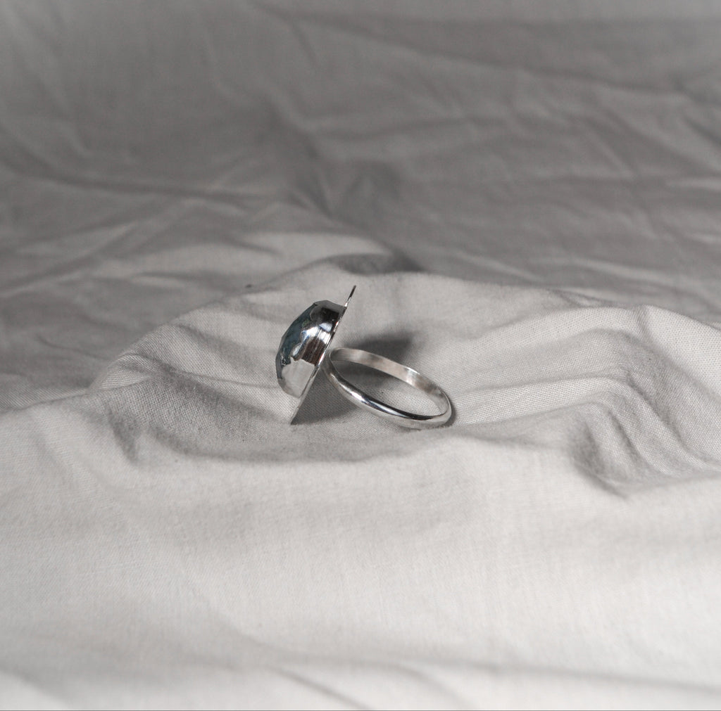 Silver ring on a textured white fabric surface