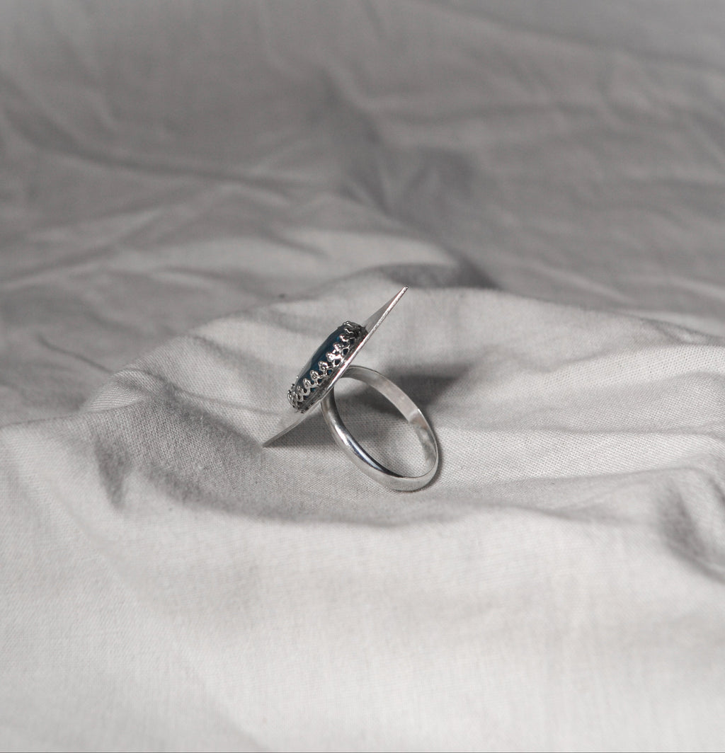 Silver ring with blue gemstones on a textured gray fabric background