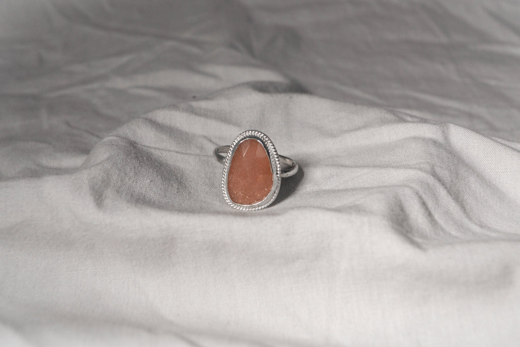 Ring with a peach stone on a gray fabric background